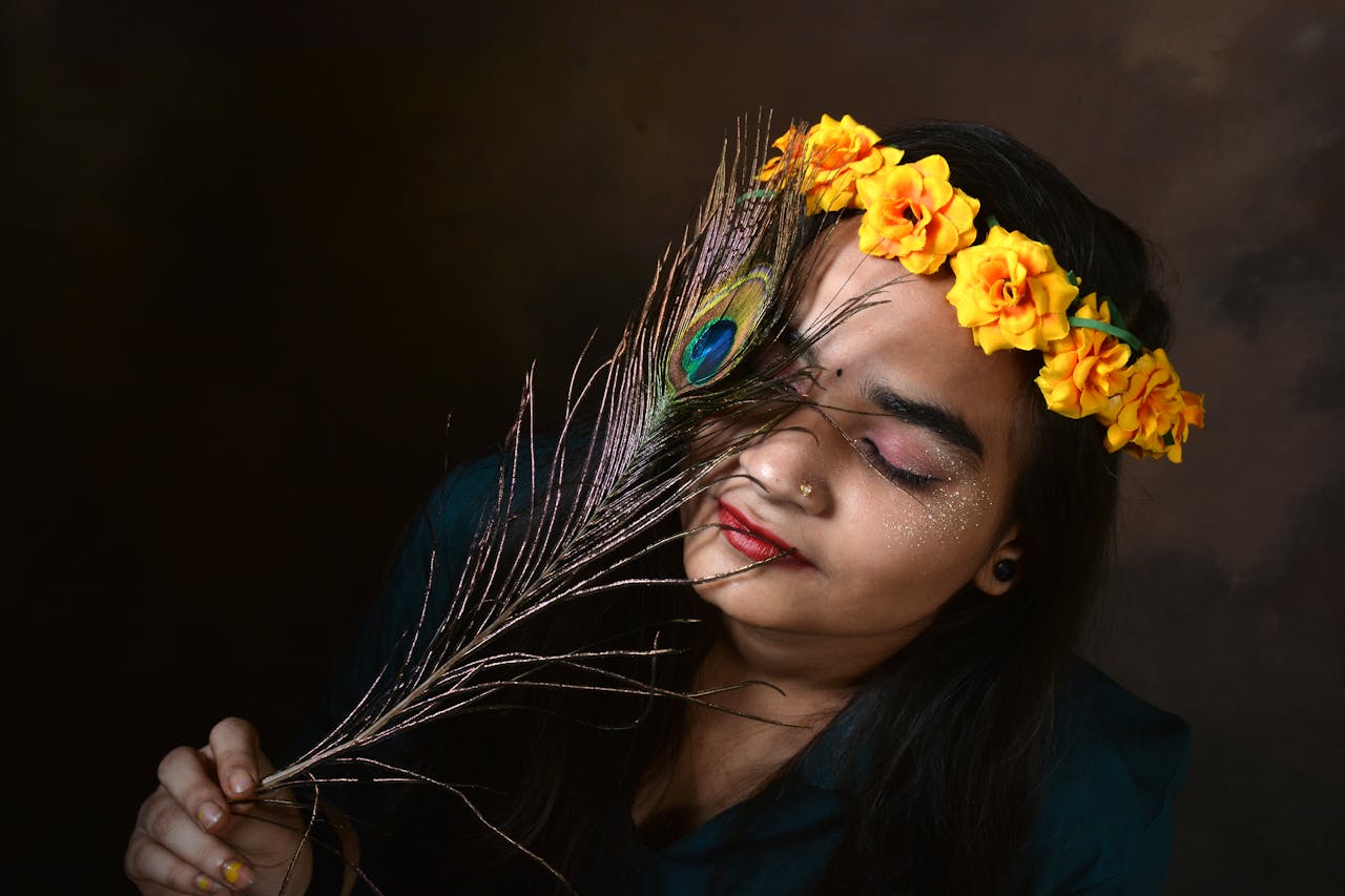 A woman adorned with a floral crown holds a peacock feather, embodying grace and cultural beauty.
